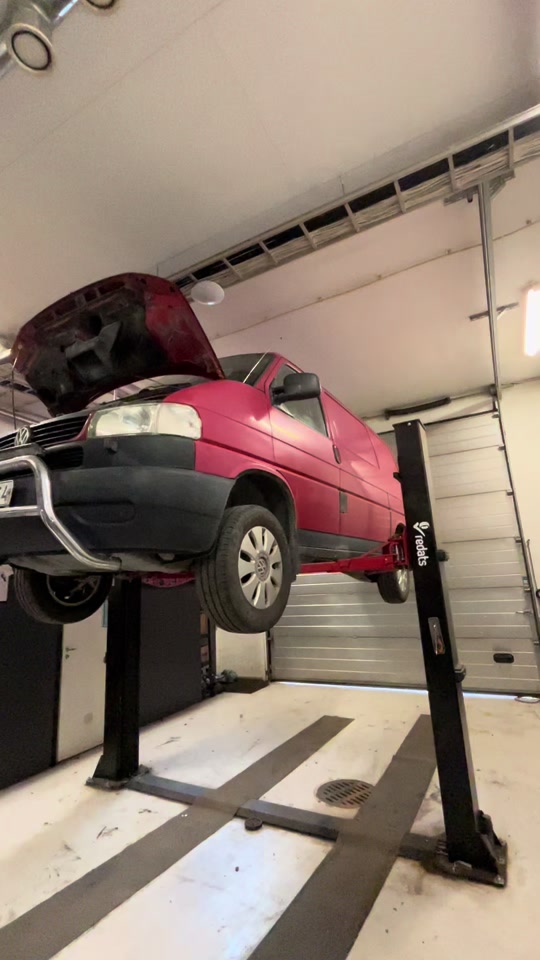 Punainen pakettiauto nosturilla HRM Autopalvelun hallissa